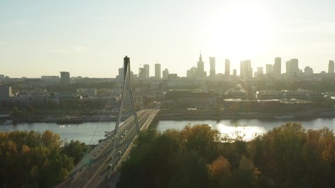 Drone flies over a bridge with a highway and city transport in Warsaw, Poland.  Beautiful landscape with bridges and the city at sunset.