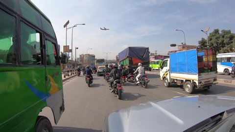 KATHMANDU, NEPAL - OCTOBER 24th, 2019. Typical colorful street scene in Kathmandu, Nepal, traffic rush in the street, passenger plane flying, truck, bus, motorcycles and cars