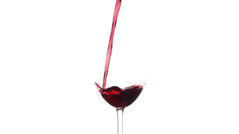 Slow motion of pouring red wine from bottle into goblet on white background
