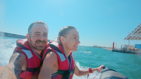 Couple rides on fun water ski jet in marina of big vacation holiday city, skyline in background. laugh and smile have good time enjoy summer vacation. Barcelona, Spain - August 21,2019