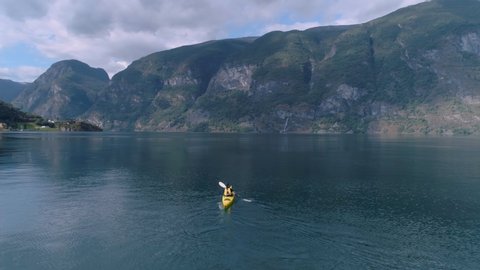 Side shot follows young athletic man during leisure vacation outdoors, healthy and sporty lifestyle choice, spending time in nature, kayak or canoe in norway fjord