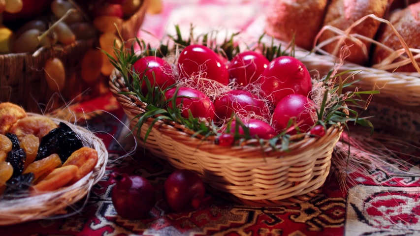 A kid putting a red-colored egg into a basket of eggs which is on a traditional Armenian Easter table. Royalty-Free Stock Footage #1041343780