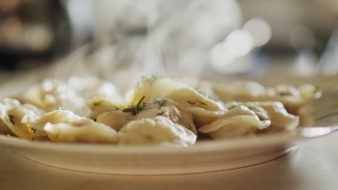 Freshly cooked steaming ravioli or pelmeni on a plate on a table, close-up soft-focus shot
