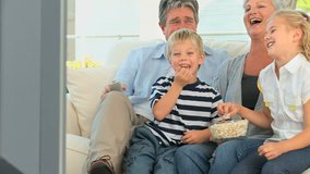 Family watching tv while eating popcorn in the living room