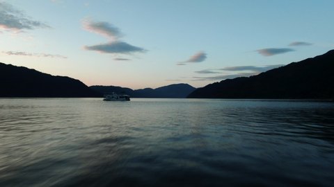 Aerial Drone Shot of Houseboat on Shuswap Lake at Dusk with Mountain Range in the Background