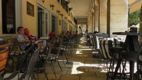 KERKYRA, GREECE - JULY 08, 2019: The streets of the old city of Kerkyra (Corfu Town), the main city of the island of Corfu. People are sitting in a cafe on Liston Street