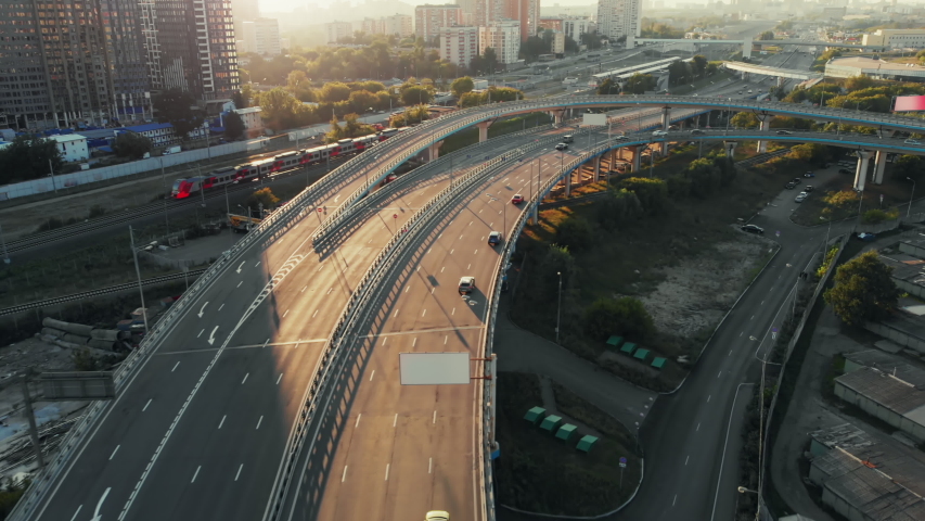 Beautiful top side view to the cars driving on multi-level highway on the sunny evening in Moscow. Picturesque aerial panorama of the road traffic and sunset city. Royalty-Free Stock Footage #1041369862