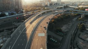 Beautiful top side view to the cars driving on multi-level highway on the sunny evening in Moscow. Picturesque aerial panorama of the road traffic and sunset city.