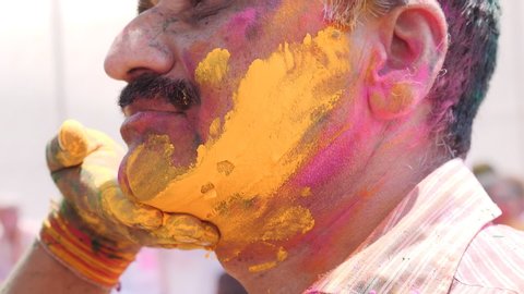 JAIPUR, INDIA - MARCH 21, 2019: slow motion close up of yellow powder being smeared on a man's face during holi celebrations in jaipur, india