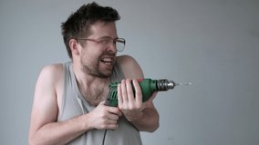 Crazy young man in big glasses pretending that he is drilling neighbours wall at night. Bad neighbour concept. Studio video