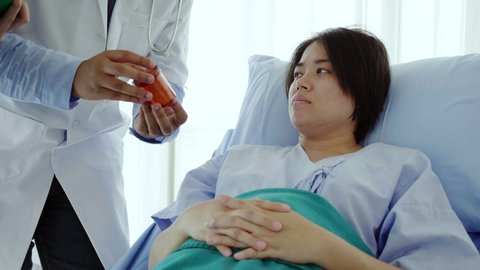 Asian woman lying on a hospital bed Listening to the doctor stand by to talk to explain about medical treatment, health care The use of appropriate drugs for cancer and HIV. Health insurance concept