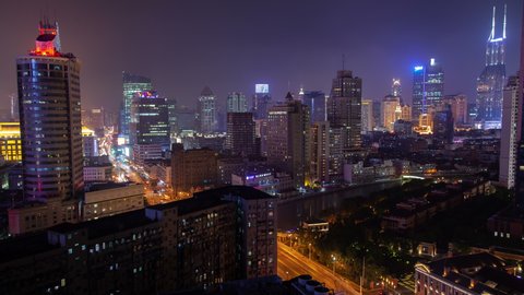 Timelapse Shanghai city buildings with bright night illumination and flashing advertisements surround calm Wusong river in China at night