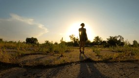 romantic mood girl in short dress goes balancing in one line on overgrown asphalt in rays of sunset 