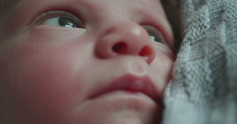 Authentic macro shot of a cute newborn baby is looking around and in the camera.Concept of children,baby, parenthood, childhood, life