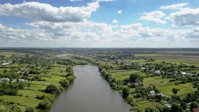 Panoramic view from drone above rural landscape of country is situated in a river valley with farming lands and farmhouses in a sunny summer day. 4K UHD video 3840, 2160p.