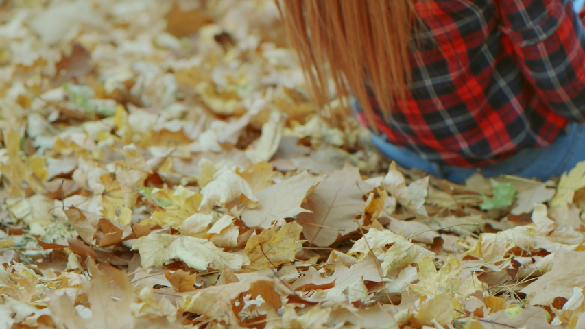 Portrait of beautiful woman with red hair lying in yellow autumn leaves. Female model enjoying life outdoors nature background 4k slow motion