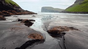 Incredible view in low tide time on Atlantic ocean coast near village Tjornuvik. Famous rock formations Risin and Kellingin Eidiskollur on background. Faroe Islands, Denmark. UHD 4k video