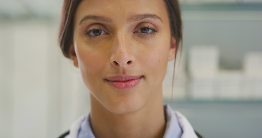Close up of an young female pharmacist consultant is smiling in camera in a drug store.