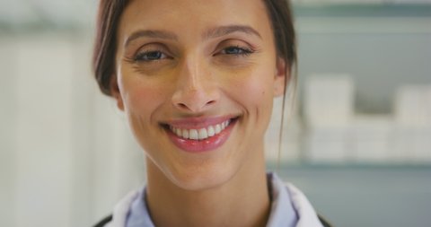 Close up of an young female pharmacist consultant is smiling in camera in a drug store.