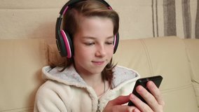 teenage girl listening to music in wireless headphones sitting on the couch
