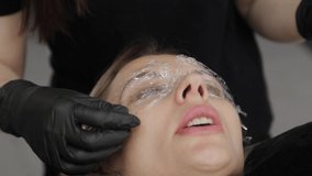 Professional beautician in a beauty salon closes the eyes of the client with a special film.