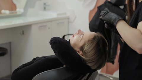 A professional beautician in a beauty salon performs eyelash lamination procedure.
