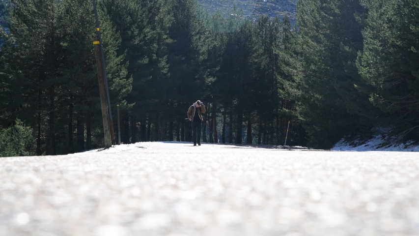 Young man walking on road surrounded by forest