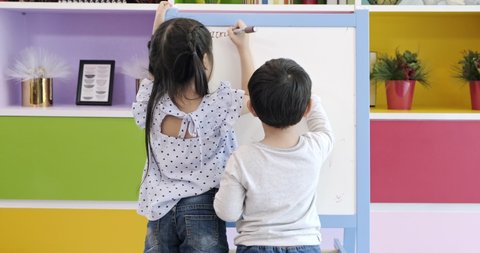 Children drawing on board. Asian boy and girl drawing on white board at home, for home learning concept. Drawing together.