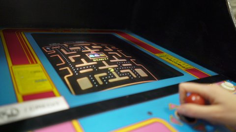 HELSINKI, FINLAND - NOVEMBER 15, 2019: Young woman playing Pacman vintage game on old 80s slot game machines in Messukeskus exhibition center.