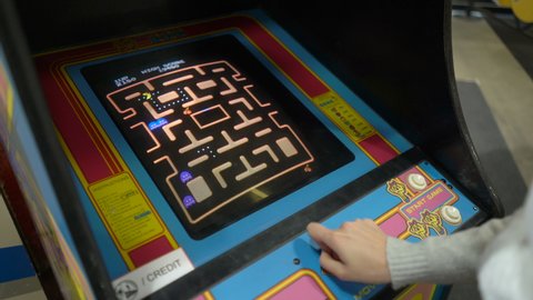 HELSINKI, FINLAND - NOVEMBER 15, 2019: Young woman playing Pacman vintage game on old 80s slot game machines in Messukeskus exhibition center.