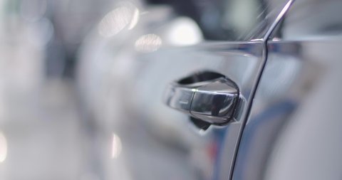 Close-up of black car door handle opened by male Caucasian hand, man sitting into the salon and closing door. Car dealership, car business. Cinema 4k footage ProRes HQ.