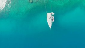 Sailing yacht moored to the shore, a delightful seascape drone video. Clear blue sea