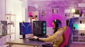 Man relaxing playing video games after a stressful day at work. Room with colorful neon lights.