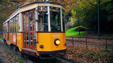 Milan, Italy November 22, 2019: Old yellow tram traffic. Autumn morning in the city of Italian fashion. Autumn trees in the city. A tree lined city alley with a characteristic tram. Public transport