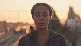 Calm athletic african american woman in sportswear opening her eyes while standing outdoors