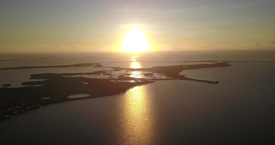 Drone footage of an orange sunset over a set of islands in the florida keys.  