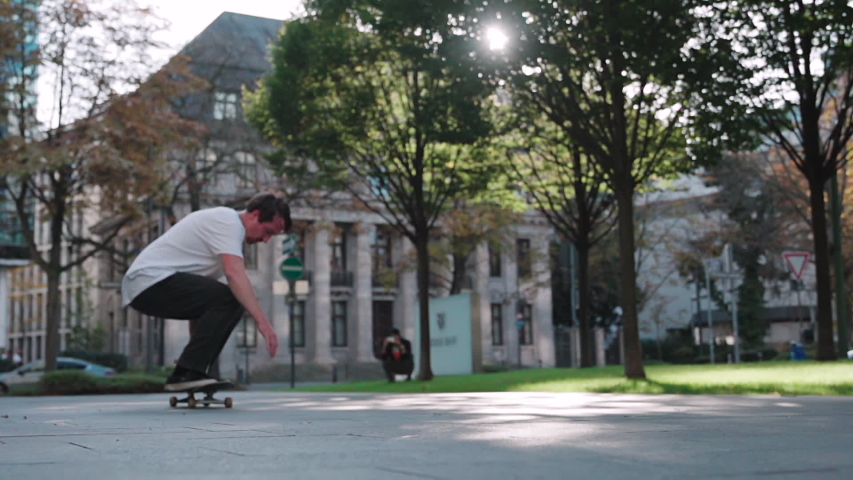 skateboarder doing flip trick in super slow motion at downtown city reflecting sun in HD