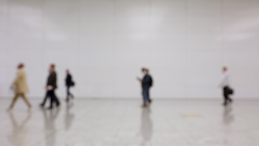 Blurred crowd of people passing by in one direction in the hallway of a convention center (HD)