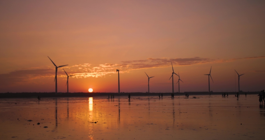 Wind turbines during a beautiful sunset at the Gaomei Wetlands by Taichung, Taiwan.  Alternative and renewable green energy production for Taiwan. Sustainable electricity generation with wind farm.