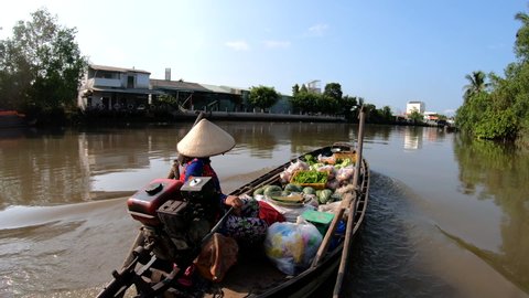 Local Vietnamese homes and villages served by small floating markets carrying fresh fruit and vegetables in motorized vessels Mekong river Vietnam travel and tourism
