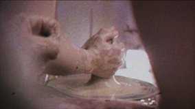 Vintage effect. A potter teaches a woman to make clay dishes. Glitch. Family video archive. Retro. A man takes a woman's hands. Ceramist makes a jug of clay on a potter's wheel. Family business.