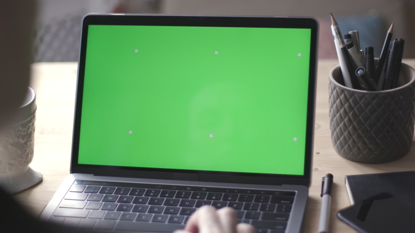 Over the shoulder shot of young woman working on modern laptop with green screen mock-up. Hands on keyboard. Royalty-Free Stock Footage #1041484186