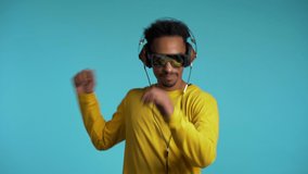 African american man with headphones dancing with hands isolated on blue background. Party, music, lifestyle, radio and disco concept.