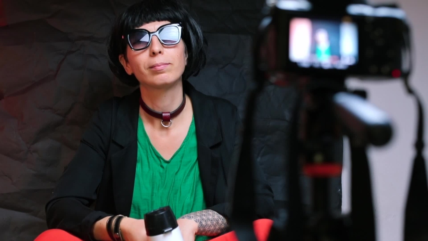 An emotional blogger in black glasses with a megaphone in his hands talks about the topic. Black background.