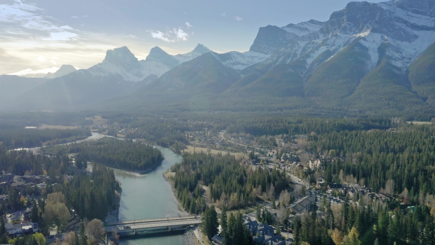 Aerial flying over the town of Canmore and Bow River near Banff. The town is surrounded by the Canadian Rocky Mountains. Alberta, Canada.  Royalty-Free Stock Footage #1041503836
