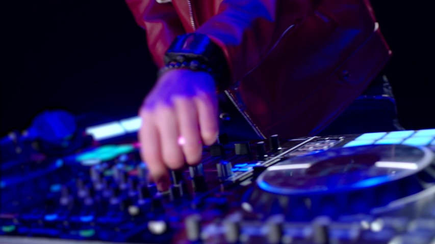 Close-Up of Dj Mixer Controller Desk in Night Club Disco Party. DJ Hands touching Buttons and Sliders Playing Electronic Music . Amazing Close Up of DJ Hands Mixing and Scratching Music on Vinyl Plate Royalty-Free Stock Footage #1041509965