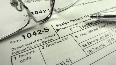 Northamptonshire UK - November 21 2019: Examining a Department of the Treasury Internal Revenue Service IRS form 1042-S Foreign Person's U.S Source Income Subject to Withholding Tax form.