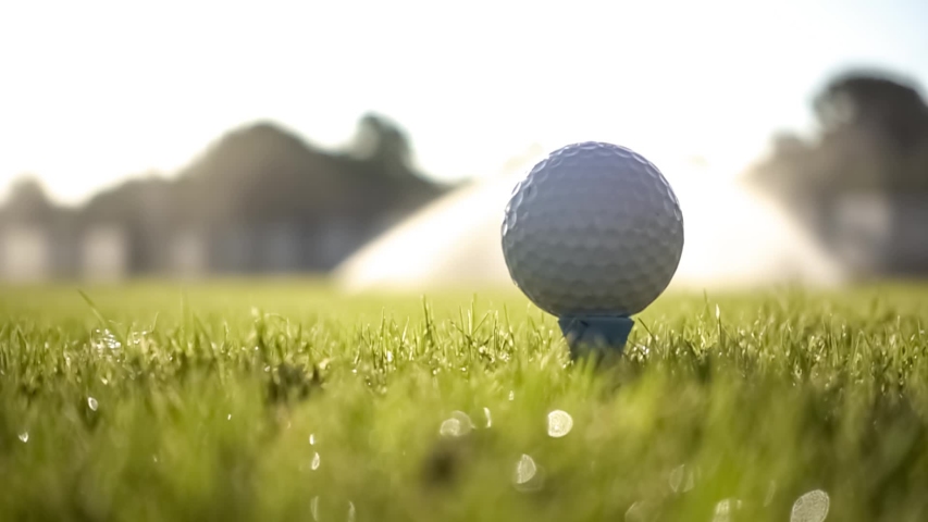 Golf club hits a golf ball in a super slow motion. Drops of morning dew and grass particles rise into the air after the impact. Royalty-Free Stock Footage #1041520816