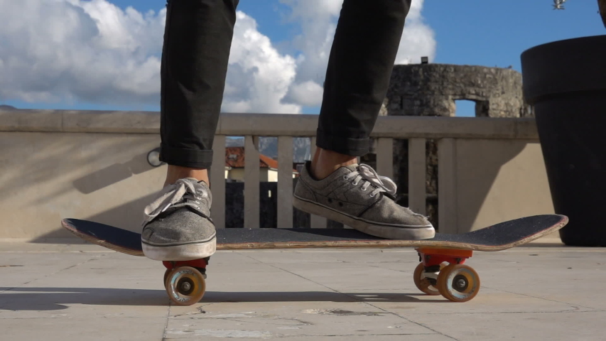 Close up of skater skateboarder man doing 360 kickflip heelflip flip trick in slow motion jump