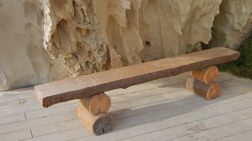 Wooden bench by the cliff. Surface sandy rock. Rocky shore of the Caspian Sea.